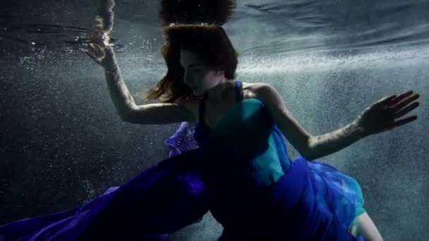 Очаровательная дама в голубом платье ныряет в глубину моря или озера, фантазии и магии — стоковое видео