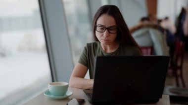 Orta yaşlı bir kadın internette dizüstü bilgisayarla sörf yapıyor, gündüzleri kafede oturuyor, internette sohbet ediyor.