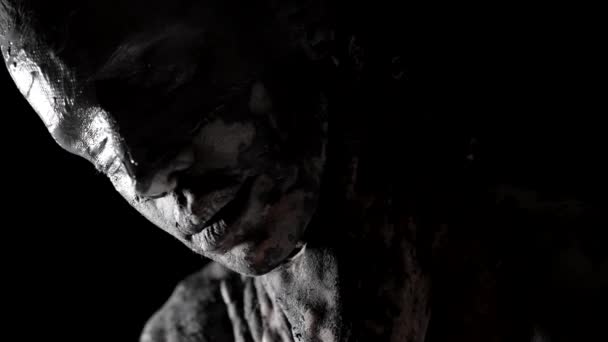 Странная женщина с повязкой на глазах и глиной на коже стоит одна в темноте, закрывая лицо — стоковое видео