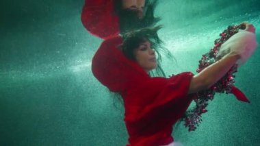 Noel Baba 'nın maskeli seksi kadını su altında süs eşyalarıyla oynuyor, havuzda ya da akvaryumda yüzüyor.