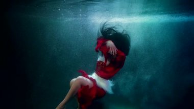 Kırmızılı zarif seksi bayan suyun altında yüzüyor, fantastik kış masalı.