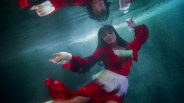 Su altı dünyasının peri masalı ve büyüsü, kırmızı elbiseli seksi bayan yalnız yüzüyor.