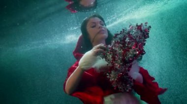 Noel gizemi, su altında neşeli bir kadının parlak süslemeleriyle oynaması.