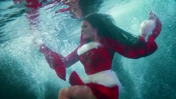 Zima podwodny strzał z piękną panią w czerwonym garniturze pływające wewnątrz zimnej wody basenu — Wideo stockowe