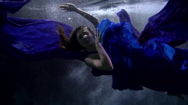 Cuento de hadas y magia bajo el agua, mujer en vestido azul está nadando lentamente en el agua — Vídeo de stock