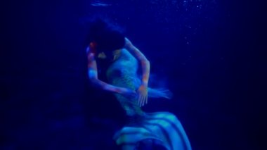 Büyük kuyruklu esrarengiz deniz kızı okyanusun mavi derinliklerinde yüzüyor, büyüleyici sualtı çekimi.