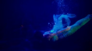 İnanılmaz su perisi okyanusun koyu mavi derinliğinde yüzüyor, yavaş çekim.