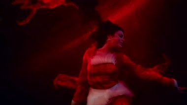 Heyecanlı seksi kadın gölün ya da nehrin kırmızı sularında boğuluyor. Su altında gizemli bir çekim.