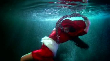 Xmas ve yeni yılın alışılmadık kutlaması, kadın suyun altında yüzüyor ve parlak süslemelerle oynuyor
