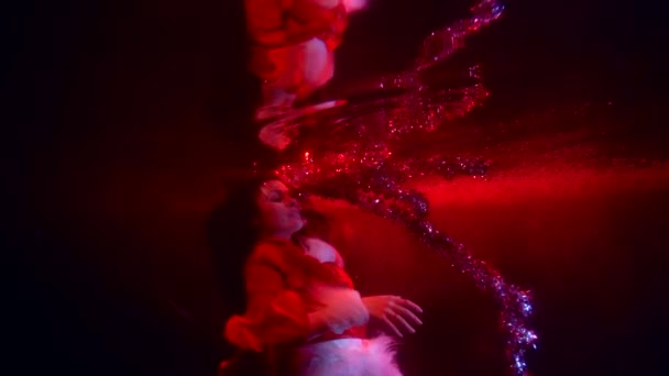 Gyönyörű nő lebeg a víz alatt, és játszik a tinsel, vörös vérű színe a víz — Stock videók