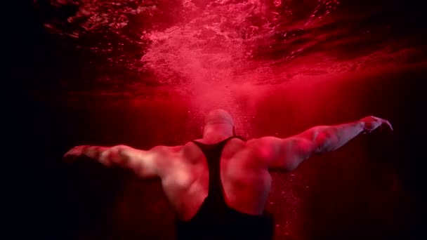 Izmos férfi elsüllyed a vörös mélységben, drámai víz alatti lövés, mozdulatlan férfi test búvárkodás — Stock videók