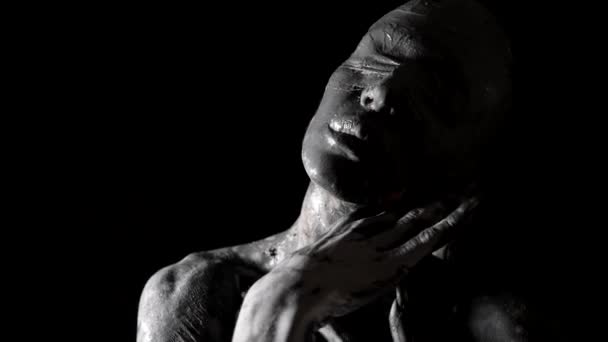 Драматический абстрактный портрет женщины с завязанными глазами с глиной на лице и руках, черно-белый снимок — стоковое видео