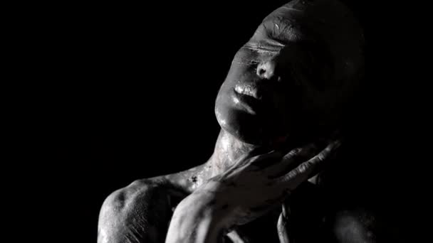 Dramatic abstract portrait of blindfolded woman with clay on face and hands, black-white shot — Stock Video