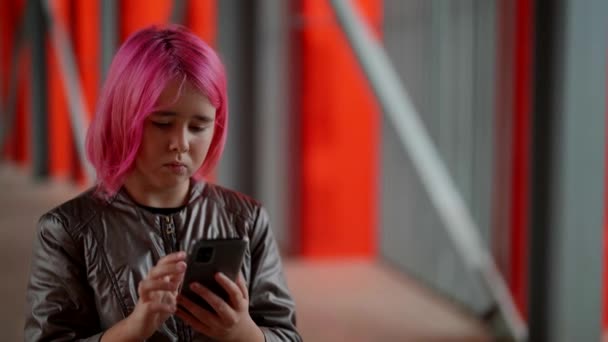Портрет красивого подростка с розовыми волосами. Девушка пишет смс на улице по телефону. Технологии, коммуникации, образ жизни и концепция людей. — стоковое видео