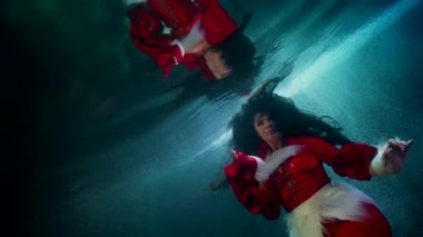 Donmuş nehir ya da gölde inanılmaz sualtı çekimi, kadın suyun içinde yüzüyor, su yüzeyine yansıyor, fantezi ve rüya sahnesi