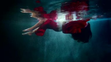 Güzel esmer kadın sihirli göl veya denizin içinde yavaşça yüzüyor, su altında fantezi sahnesi, rüya ya da peri masalı gibi.