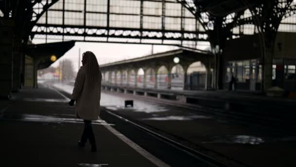 Traurige einsame Frau schlendert an Herbst- oder Wintertagen auf Bahnsteig des alten Bahnhofs — Stockvideo