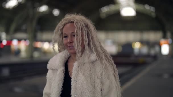 Mulher loira atraente em casaco branco está andando na estação ferroviária, close-up — Vídeo de Stock