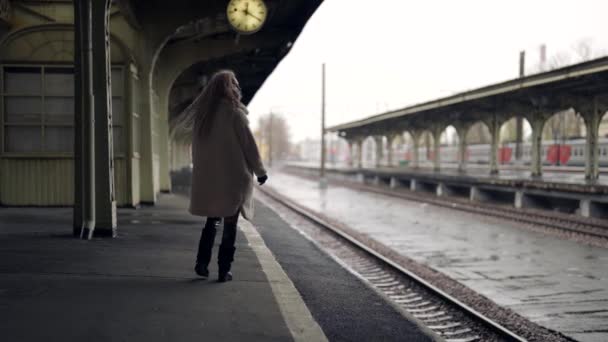 Kışın ya da sonbahar günü boş tren istasyonunda yalnız başına yürüyen yalnız bir kadın. — Stok video