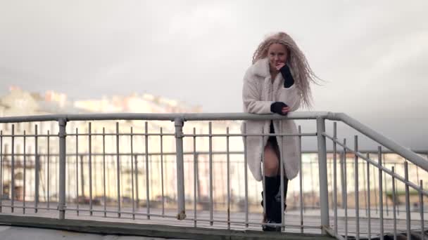Fermecător blondă doamnă în blană albă haină în urbanscape în ziua de iarnă, femeie atractivă și frumoasă — Videoclip de stoc