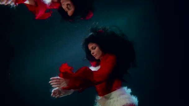 Ασυνήθιστη εικόνα της γυναίκας Σάντα, κυρία με το κόκκινο κοστούμι επιπλέει κάτω από το νερό, φαντασία αργή κίνηση — Αρχείο Βίντεο