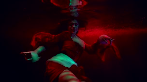 Dramatický podvodní záběr s dámou plavající v červené vodě bazénu nebo jezera, horor a strašidelný film — Stock video