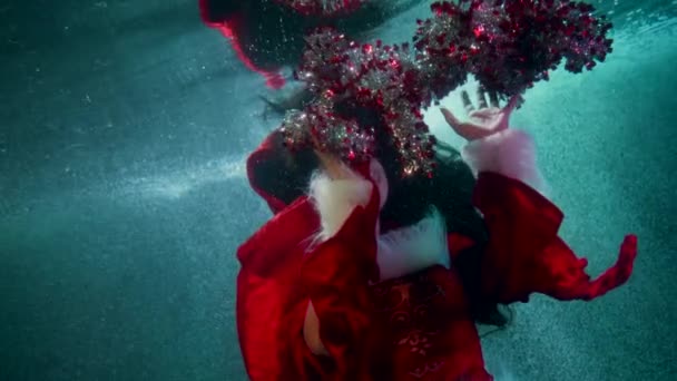 Підводний різдвяний постріл, молода красива жінка грає з мішурою, святкуючи зимовий фестиваль всередині води — стокове відео