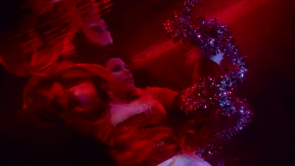 Mysterious witch is floating underwater and conjuring, playing with magical tinsel — Stock Video