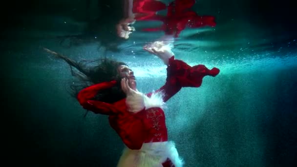 Underwater princess is playing with surface of frozen lake or river, viewing her reflection — Stock Video