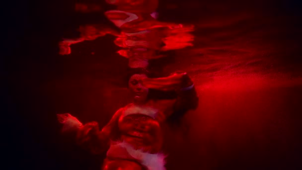Sexig dam flyter under vattnet, poserar förföriskt till kameran, dramatiskt rött ljus på vattendjup — Stockvideo