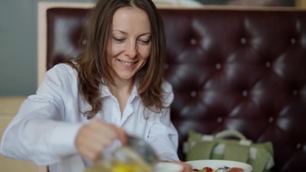 Een mooie volwassen vrouw geniet van een kopje thee bij het ontbijt in een café. Grappige levensstijl, vrije tijd in een restaurant. — Stockvideo