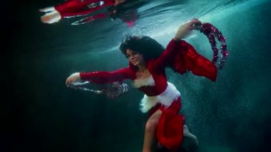 Suyun altında Noel festivali, havuz içinde yüzen kadın, kış festivalini kutluyor.