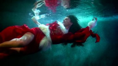 Kırmızı elbiseli çekici kadın suyun altında yüzüyor, fantastik bir kış masalı