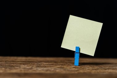 Ahşap ofis masasının arka planında boş yapışkan bir not kağıdı. Metin girmek için kullanılır.