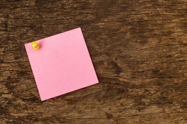 Ahşap ofis masasının arka planında boş yapışkan bir not kağıdı. Metin girmek için kullanılır.