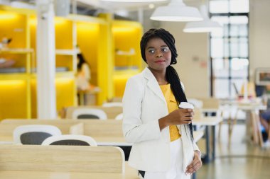 Portre mutlu gülümseme Afro-Amerikan kadın işyerinde duruyor. Ofiste gülümseyen güzel iş kadını..
