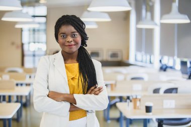Portre mutlu gülümseme Afro-Amerikan kadın işyerinde duruyor. Ofiste gülümseyen güzel iş kadını..