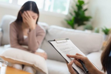 Psikiyatrist, kadın hasta terapisini zihinsel semptomlar ve depresyon için not alıyor. Panoya not alarak elinizi kapatın..