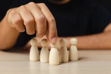 Tahta figürler takım çalışması için insan liderliği seçildi. İnsanların elleri, liderleri atamak için stratejiler geliştirmek için tahta kuklalar seçerler. Takım çalışması kavramının liderliği.