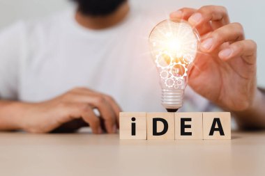 Adam tahta küplerdeki ampullere IDEA sözcüğüyle dokunuyor. yaratıcı dahi yenilik teknolojisi bilgisi başarılı oldu. sembol düşünme yaratıcı konsept.