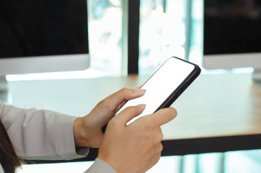 Ofis odasında beyaz ekranlı akıllı telefon kullanan bir kadın. İlan için cep telefonu boş ekran kullanımı. Mockup akıllı telefon.