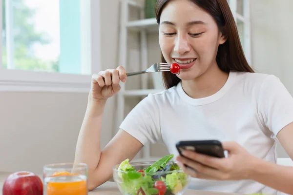 Wanita Bahagia Tersenyum Makan Buah Salad Sayuran Dan Menggunakan Smartphone — Stok Foto