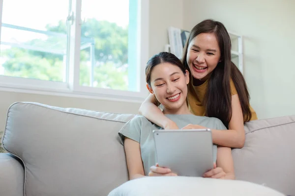 快乐的女性情侣们坐在家里的沙发上 用数字平板电脑在网上购物 漂亮女人女朋友的生活方式 — 图库照片