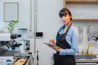 Tablet kullanarak tezgahta duran önlük giyen kadın garsonun portresi. Kadın yönetici kafe başlangıç küçük işletme çevrimiçi sipariş almak.