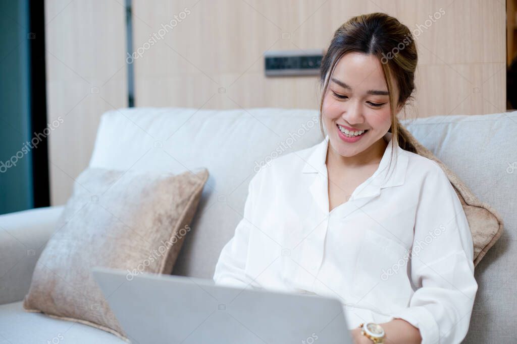Happy young asian woman working with laptop. female smiling work at home chatting social network meeting online. reading email or shopping online.