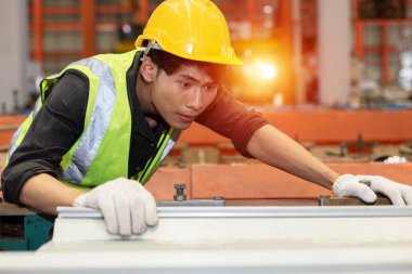 Asyalı erkek işçiler fabrikada demir üretimini kontrol etmek için kırmızı kask takıyorlar. Ağır Sanayi Üretim İşyeri.