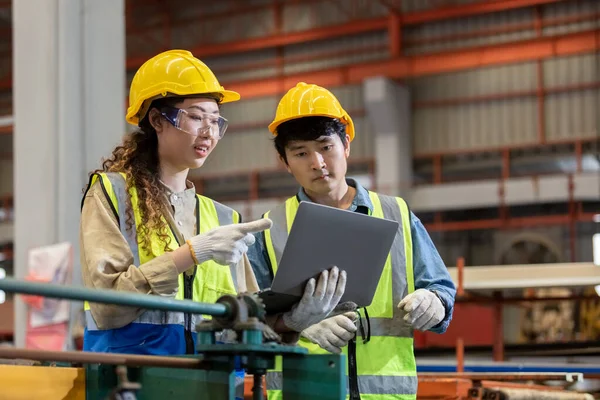 Erkek ve kadın mühendis imalat fabrikasında çalışırken dizüstü bilgisayar kullanıyor. Ekip çalışması teknisyeni metaller otomatik mekanik enerji projesi.