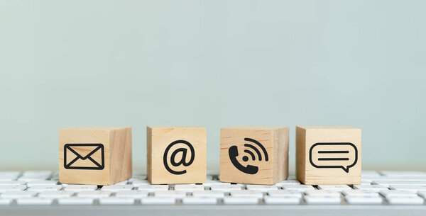 Concept of contact us. wooden cube blocks with contact icons on computer keyboard. symbol of connection, email telephone and dialog box. Technology social network.