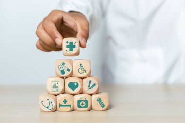 Tıbbi ve sağlık hizmetleri kavramı. Doktor elinde tıbbî simgelerle dolu tahta küp blokları tutuyor. tedavi ve ilaç sembolleri.