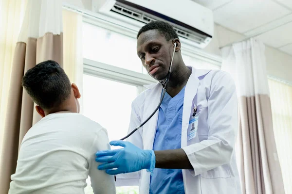 African American medical male doctor use stethoscope checkup diagnosis child boy patient. health medical hospital concept.